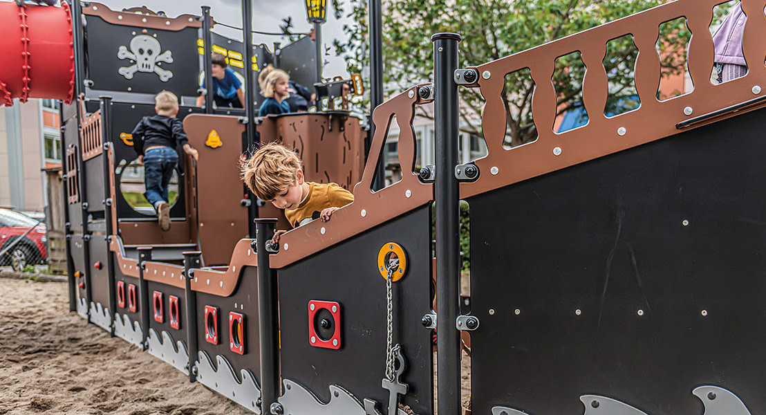Børn leger på skolens legeplads, som er designet som et stort piratskib.