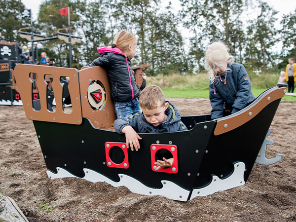 Legepladsens legehus er designet som et lille piratskib hvor tre børn leger.