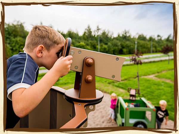 Barn spejder over legeplads gennem kikkert, som er en del af et jungle legesystem.