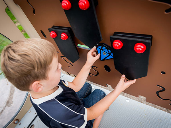 Dreng leger med aktivitetspanel på legesystem.
