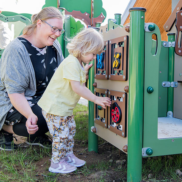 Legestation hvor pige leger med vendespil sammen med pædagog.