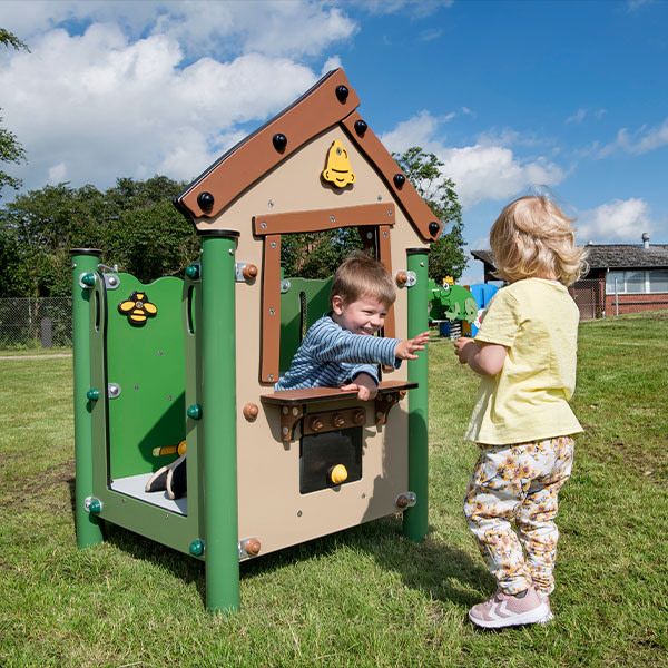 Legestation på græs hvor to børn leger ved købmandsdisken.