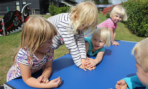 Børnene sidder samlet omkring bord bænkesættet og snakker.