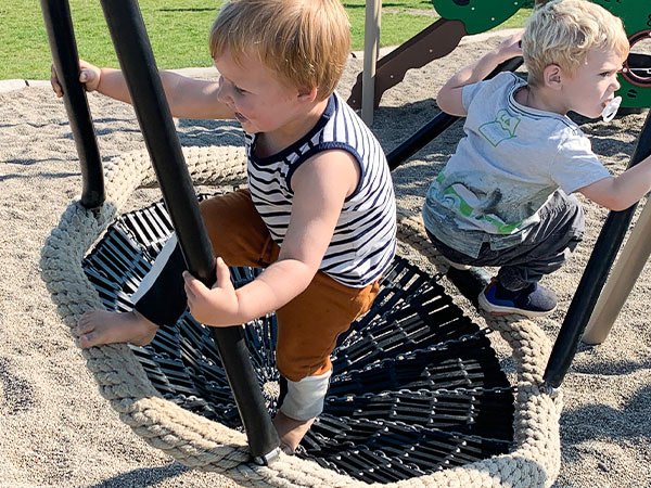Børnene skubber gang i gyngen på legepladsen.