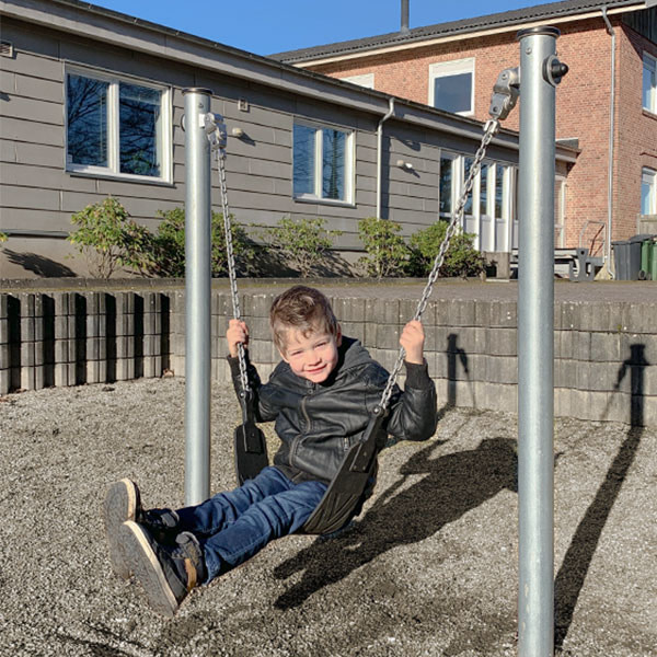 Drengen tager en gyngetur på det lille gyngestativ.