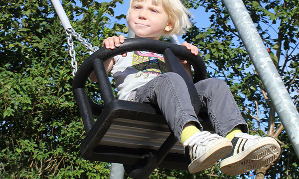 Gyngesædet til små børn giver pigen en sjov gyngetur.