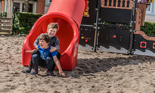 To drenge rutsjer igennem tunnerutsjebanen på skolens legeplads.