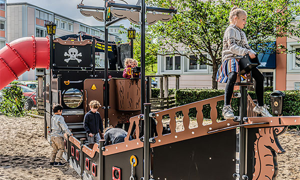 Børn leger på ledon legeredskaber på offentlig legeplads.