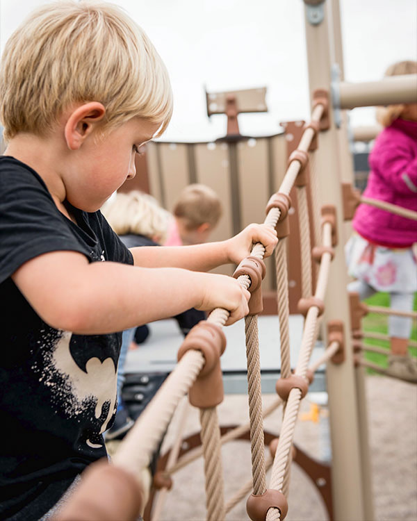 Børn leger i klatretårn på legepladsen.