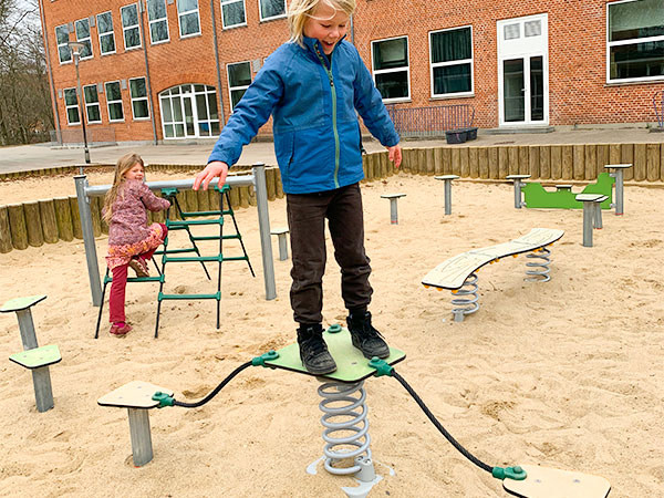 Dreng balancerer på legeplads.