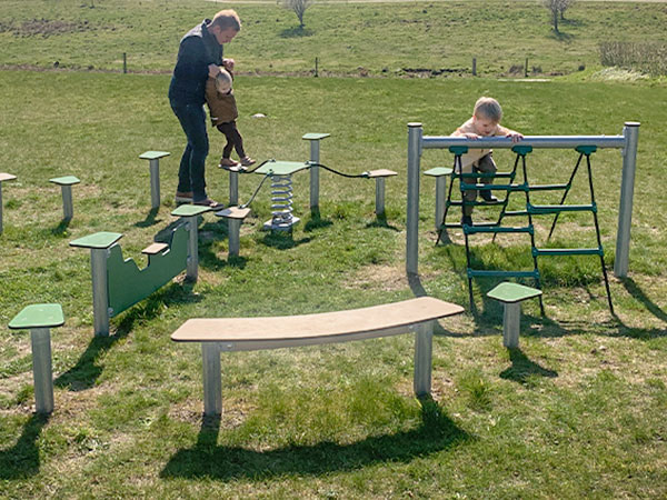Børn leger på udendørs forhindringsbane på legepladsen.