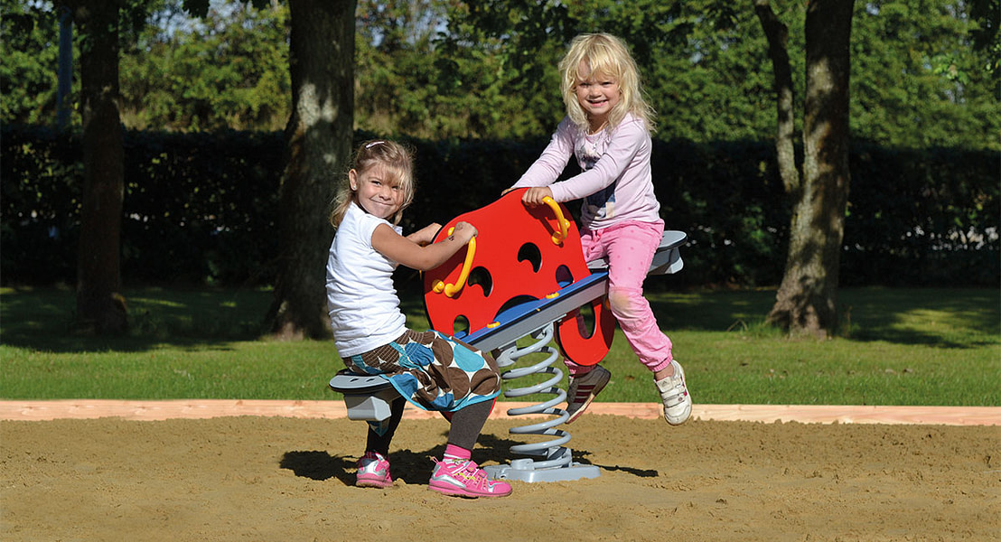 To piger leger på en vippe til legeplads.