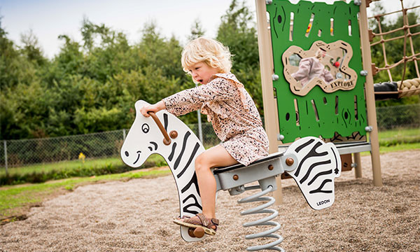 Pige vipper på zebra vippedyr på jungle legepladsen.